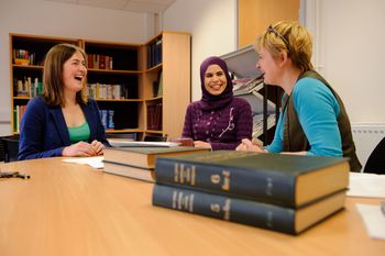 Photograph showing three people sat in the library.
